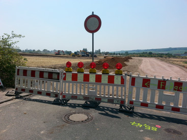 Das Bild zeigt die noch gesperrte Erschließungsstraße für ein neues Baugebiet 