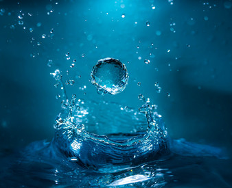 Fakten zum Zukunftsplan Wasser Wassertropfen trifft auf Wasseroberfläche und spritzt auf. Blaues Licht betont Bewegung und Dynamik.