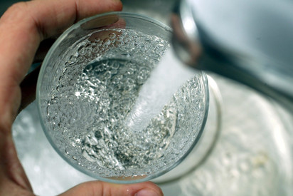 Trinkwasser Glas wird mit klarem Wasser aus Wasserhahn gefüllt. Nahaufnahme von Hand, Glas und Wasserstrahl.