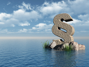 Großes Paragraphen-Symbol auf Felsen in Wasser. Blauer Himmel mit Wolken im Hintergrund.