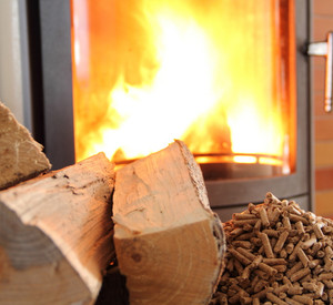 Holzscheite und Pellets vor einem Ofen